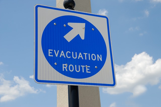 a white sign with a blue circle inside. The text inside the circle is white and says Evacuation route